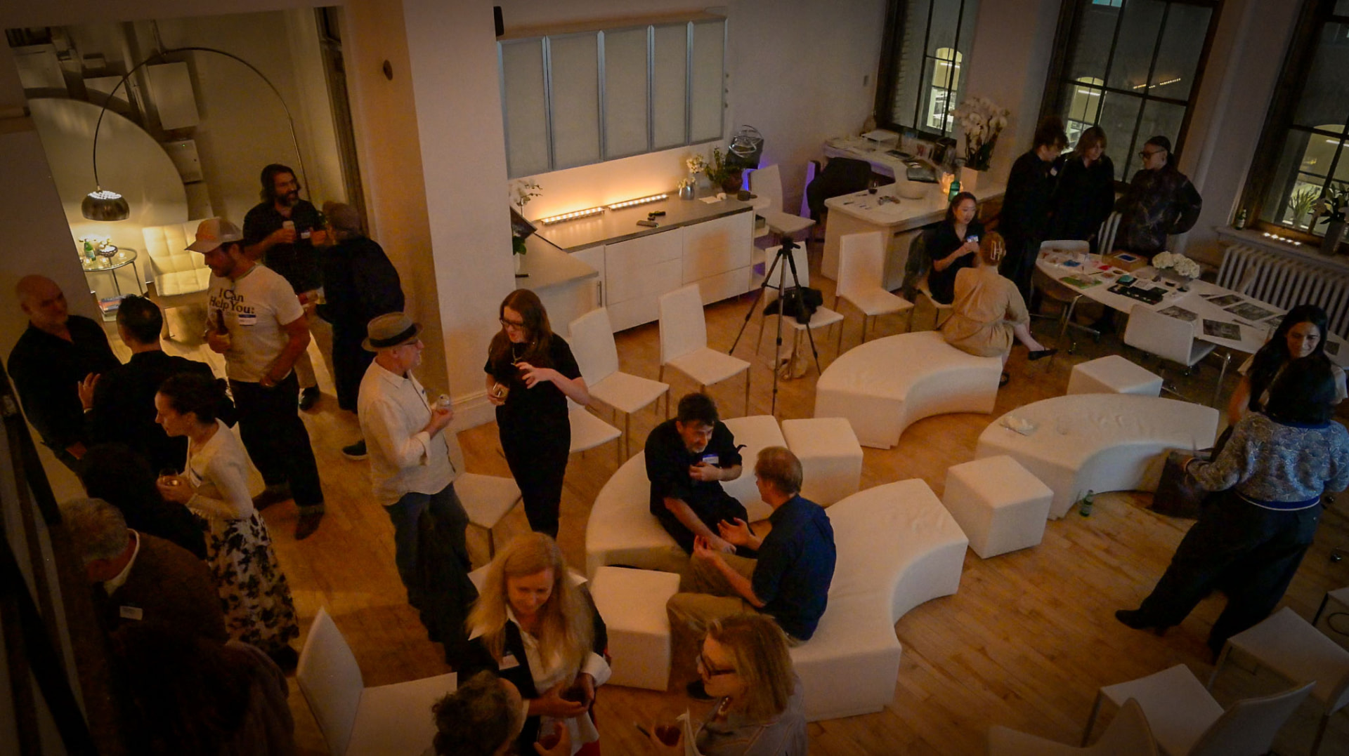 Guests talking around a table of objects in a loft, seen from above